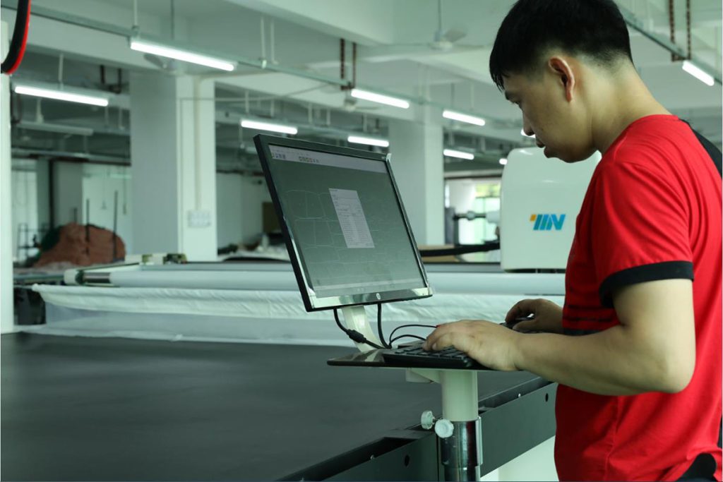 Garments factory worker operation in computer to start the machine cut the fabric according to pattern